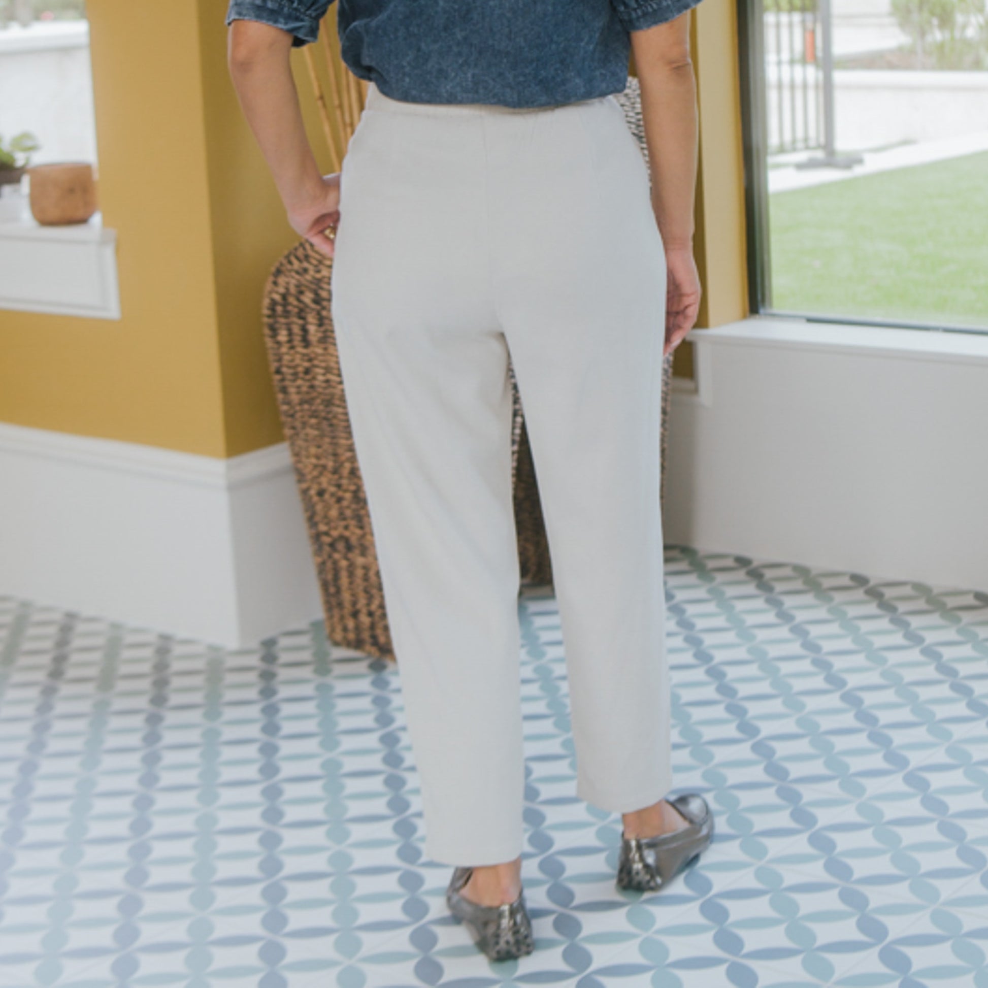 Person wearing beige pants standing on a patterned floor.